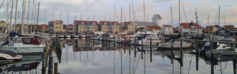 Panoraudsigt over Sæby Havn, hvor vand, lystbåde og huse ved havnen toner frem