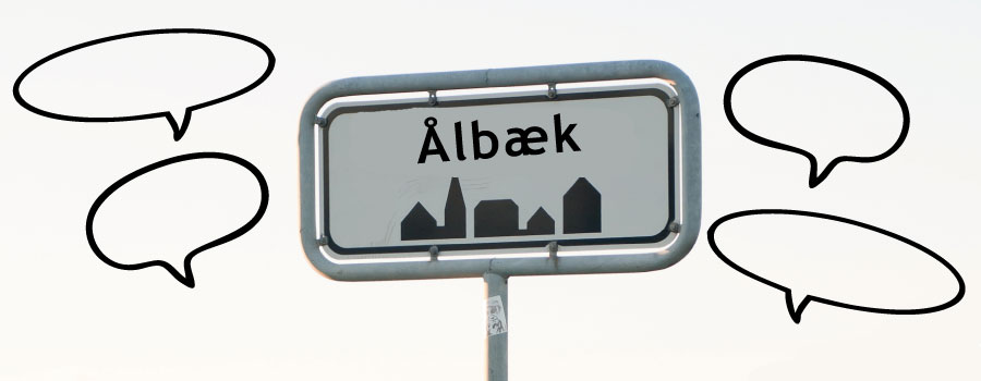 Ålbæk-byskilt med talebobler omkring.
