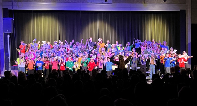 Et kor af børn står på scenen og synger