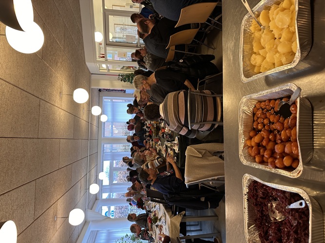 Gæster til julefrokost foran bord med julemad